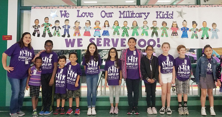 Students in front of a banner that reads "We love our Military Kids"